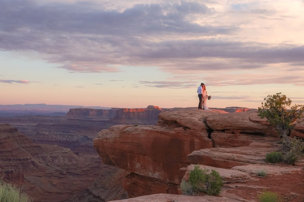 Scenic desert landscape with red rock formations and dramatic clouds at sunset in Utah's Canyonlands National Park.