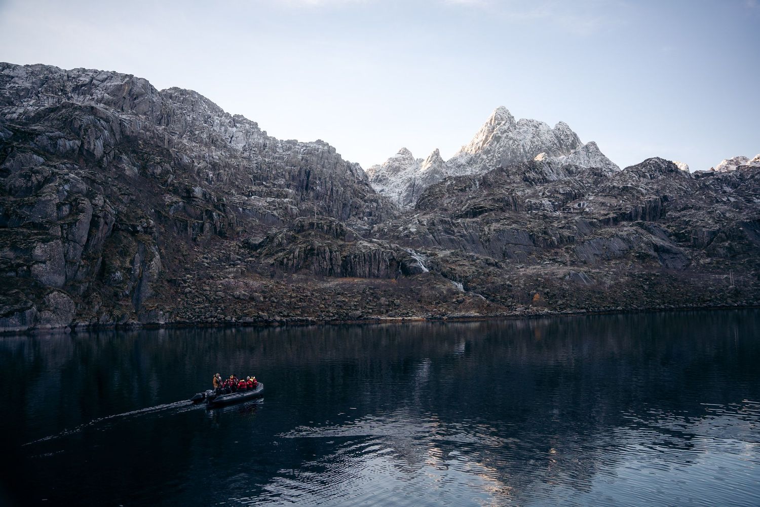 zodiac qui navigue dans le trollfjord avec sommets enneigés