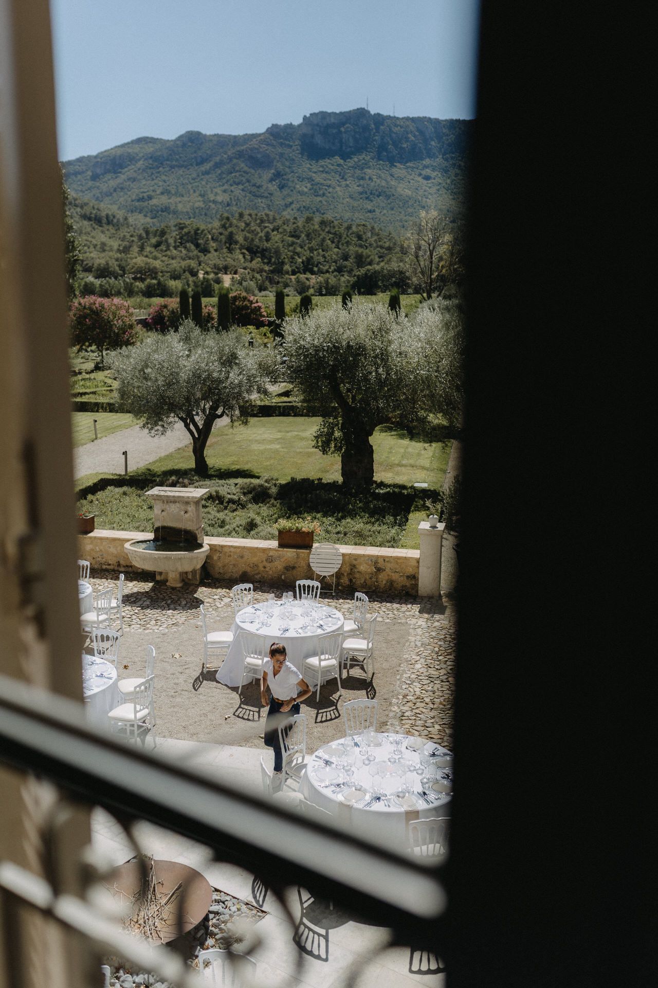 Outdoor wedding reception setup with round tables and chairs overlooking a scenic mountain landscape.