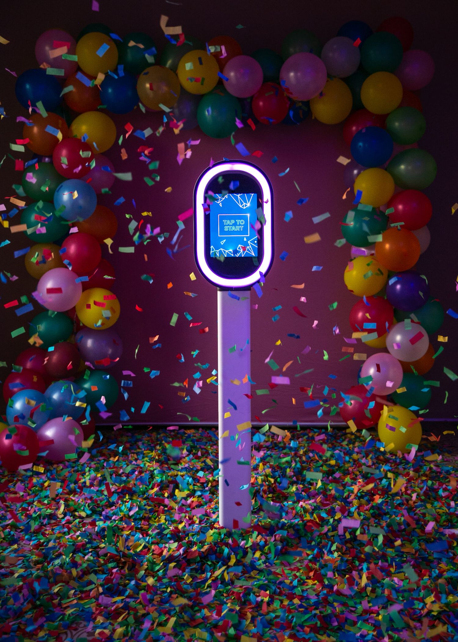Colorful confetti and balloons create a festive scene with glowing neon signs against a dark background.