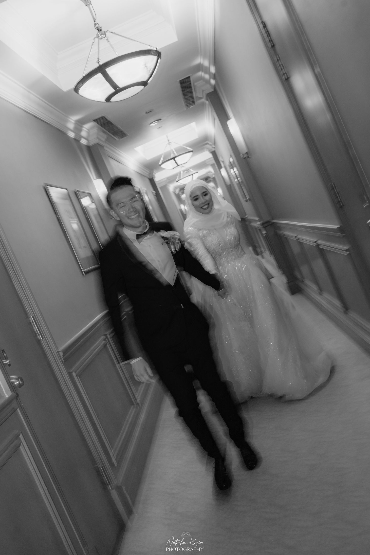 A sequence of black and white photos showing a couple walking down a hotel hallway in formal wedding attire.