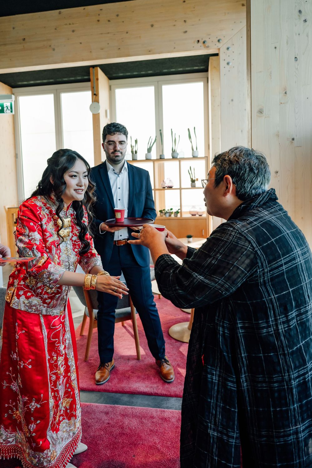 Traditional Chinese tea ceremony taking place on red carpet in wooden room.