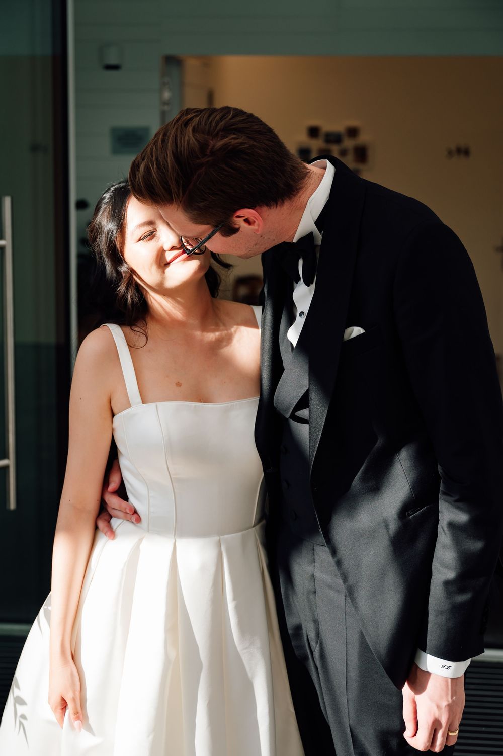 A romantic wedding couple in black and white formal attire share an intimate moment together.