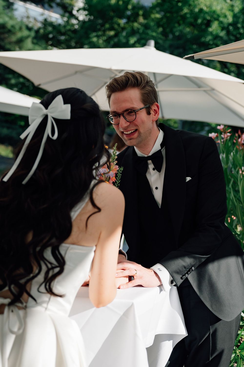 A couple in wedding attire shares an intimate moment together outdoors under white umbrellas.