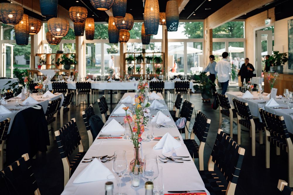Elegant restaurant interior with white tablecloths, dark wood accents, and warm lighting creates an upscale dining atmosphere.