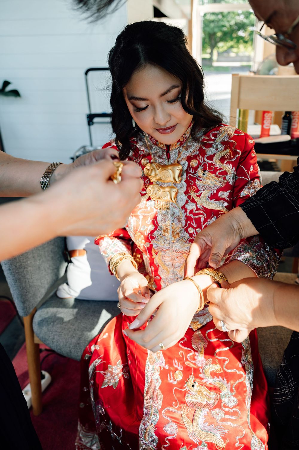 A series of photos showing someone wearing a traditional red Chinese qipao dress being helped with getting dressed.