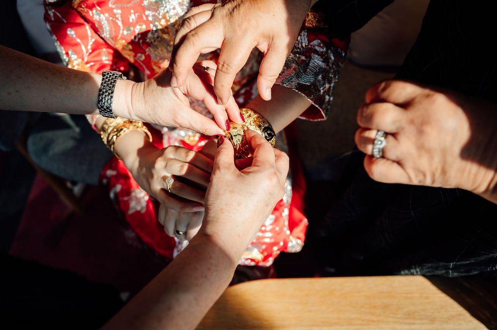 Close-up of hands sewing red and white patterned fabric with needle and thread on a wooden surface.