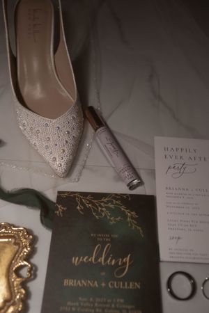 Wedding details including sparkly bridal shoes and elegant invitation suite in dark green and gold.