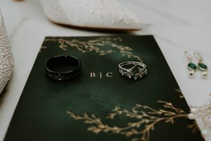 Wedding rings displayed on a dark green book with gold foil details.