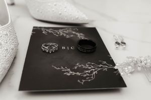 Elegant black and white wedding stationery with silver accents laid out on white surface.