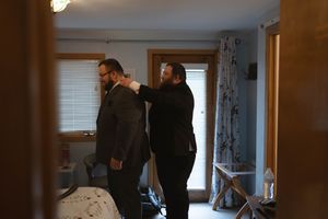 Getting ready scene in a bedroom with formal attire preparations.