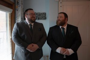 Two men in suits share a candid conversation in a formal setting.