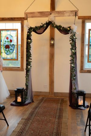 Chapel interior with wooden beams and stained glass windows decorated with green garlands.