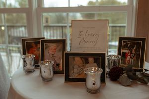 Wedding memory table with framed photos and candle holders in soft lighting.