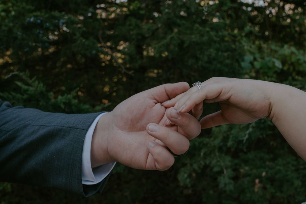 Close-up of newlywed hands touching tenderly against a natural background.