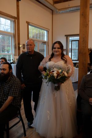A wedding ceremony in a rustic venue with exposed wooden beams and natural lighting.
