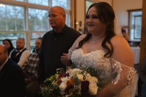 A wedding ceremony with a bride holding a beautiful bouquet of white and peach flowers.