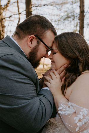 Romantic wedding portraits captured in warm sunset lighting through forest trees.