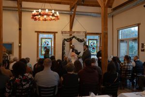 Interior view of a wedding venue with exposed beams and chandelier lighting.