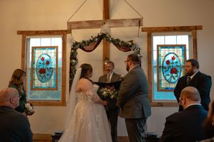 A wedding ceremony setup with elegant floral decorations and guests gathered in a bright indoor venue.