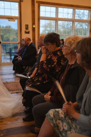 Wedding guests seated in rows watching an emotional ceremony in a sunlit venue.
