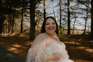 A joyful moment captured in a sunlit forest setting wearing a white lace wedding gown.