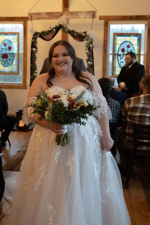 Beautiful wedding moment captured in a chapel with stained glass windows and floral bouquet.
