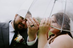 Romantic wedding photo of couple sharing an intimate moment under a clear umbrella.