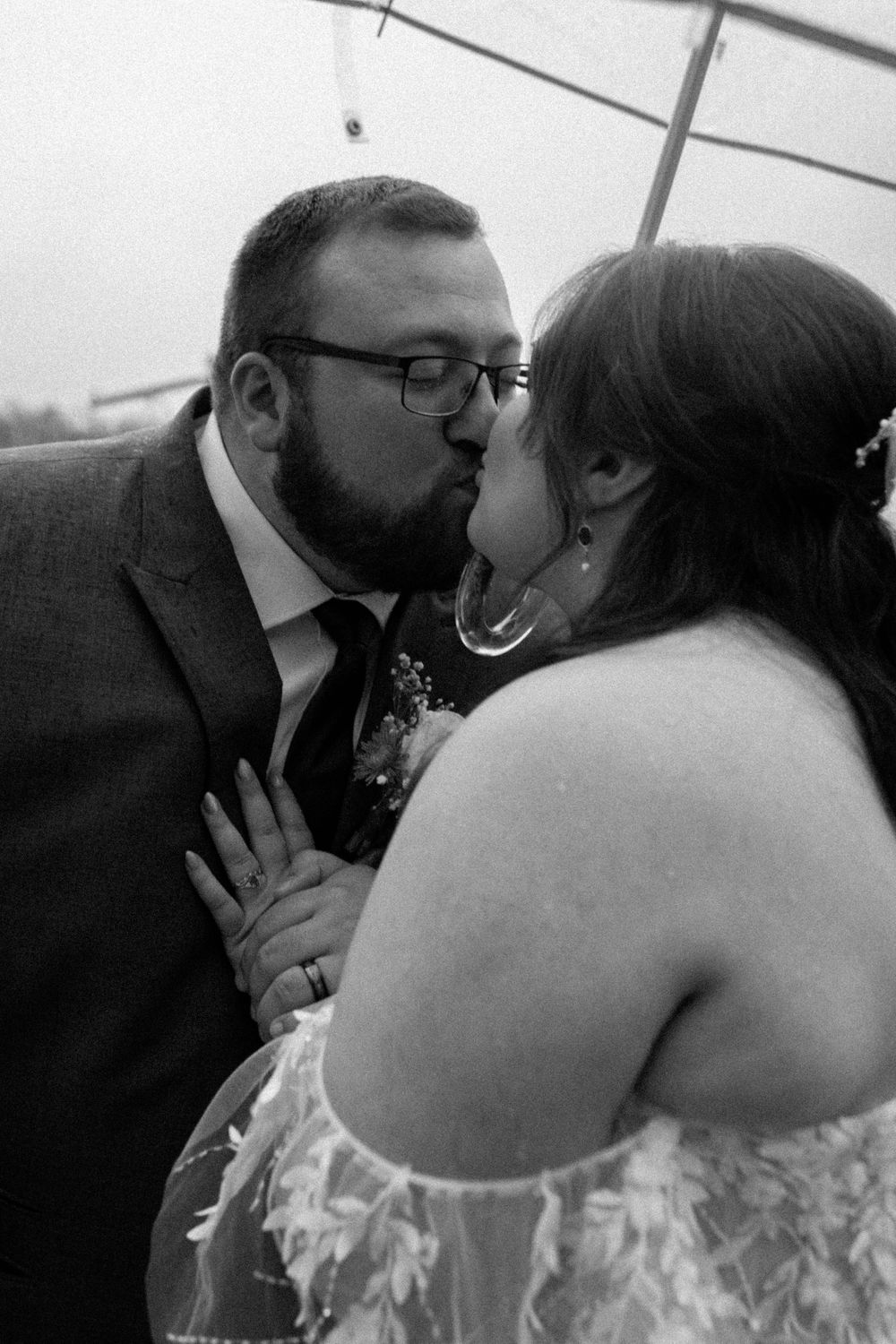 Black and white wedding portraits showing tender moments between newlyweds under an umbrella.