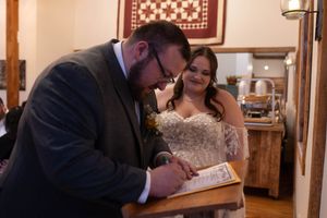 A couple signs paperwork together during their wedding ceremony.