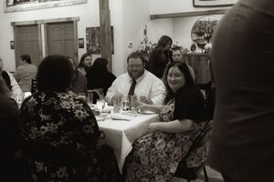 Wedding guests enjoying dinner at tables in a reception hall.