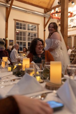 A bride in a white lace gown mingles with guests at candlelit reception tables.