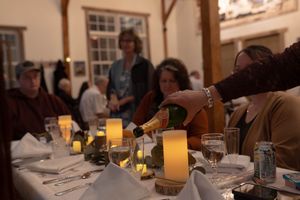 Guests pour drinks at a candlelit wedding reception table.