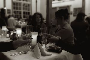 A black and white photo of guests at a wedding reception with wine glasses.