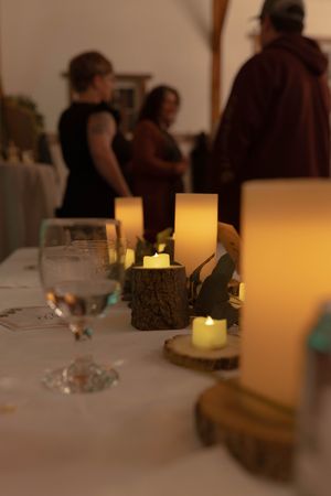 Wedding reception table settings with glowing candles and white tablecloths.
