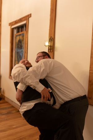 Playful dance moves being performed on a wooden dance floor at a wedding reception.