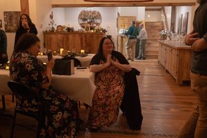 Wedding reception guests enjoying themselves in a rustic venue with wooden beams.
