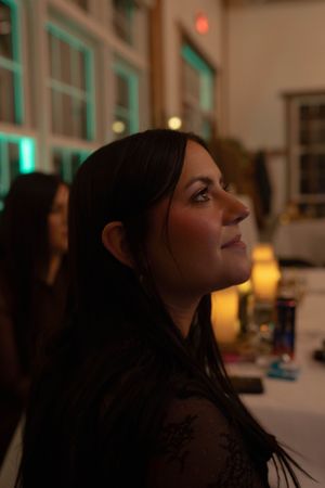 Side profile view of someone dancing in a dimly lit reception hall with green accent lighting.