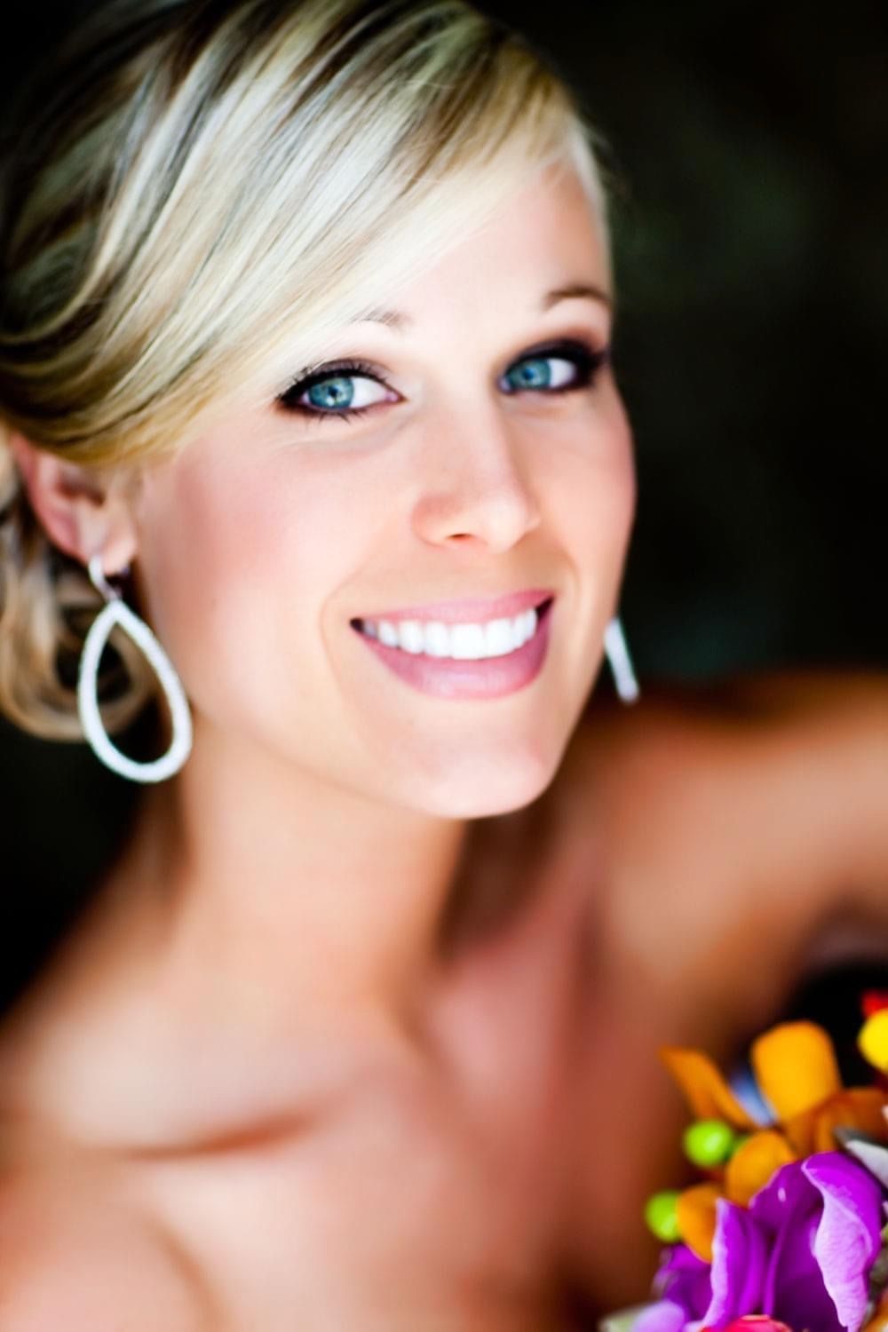 Close-up portrait shots showing bright smile and silver hoop earrings against colorful floral background.