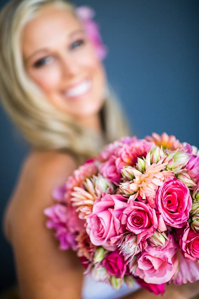 Beautiful pink and peach bridal bouquet with roses in focus against blurred background.