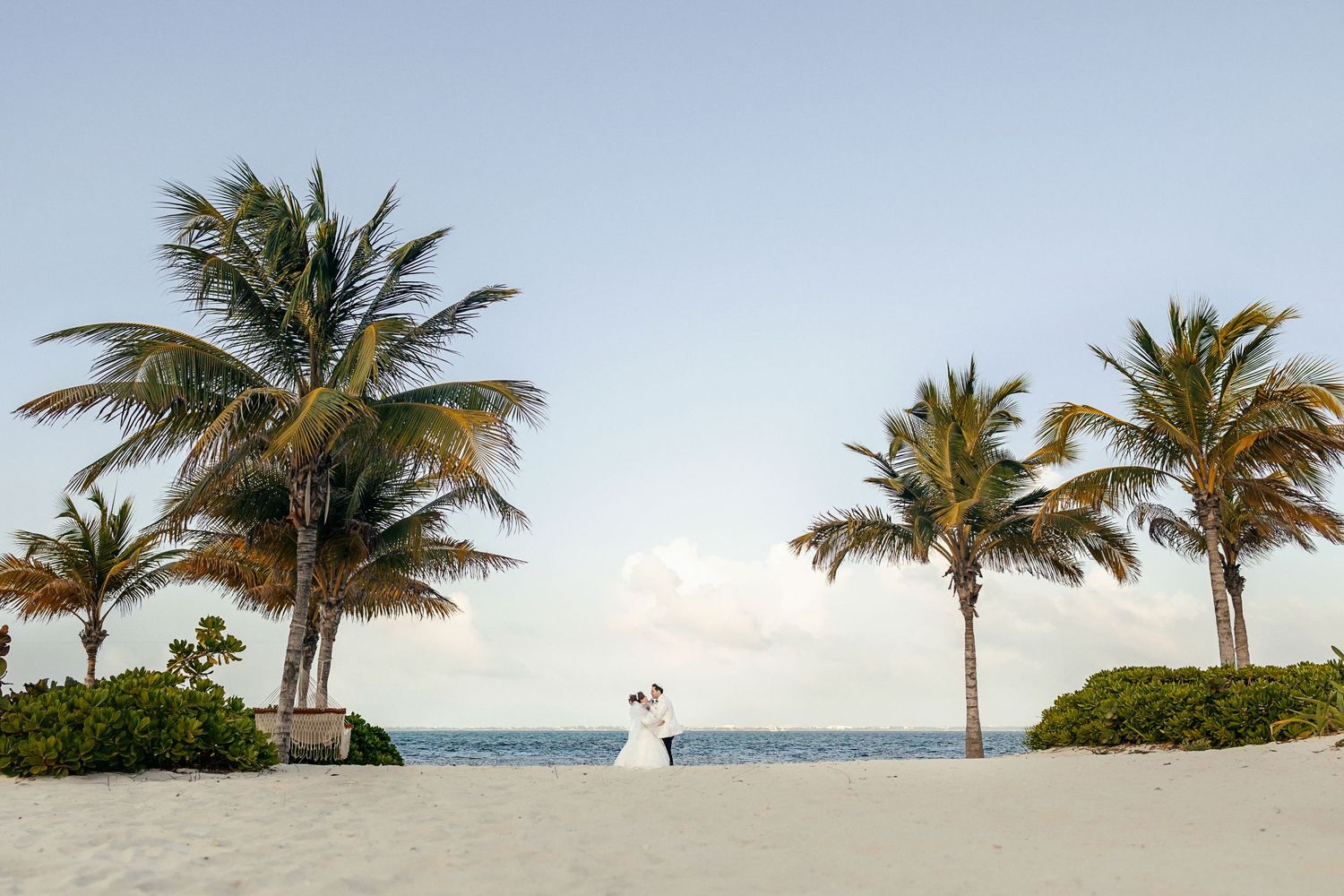 Bride and groom kiss joyfully during their ceremony exit at Live Aqua Cancún surrounded by cheering guests.