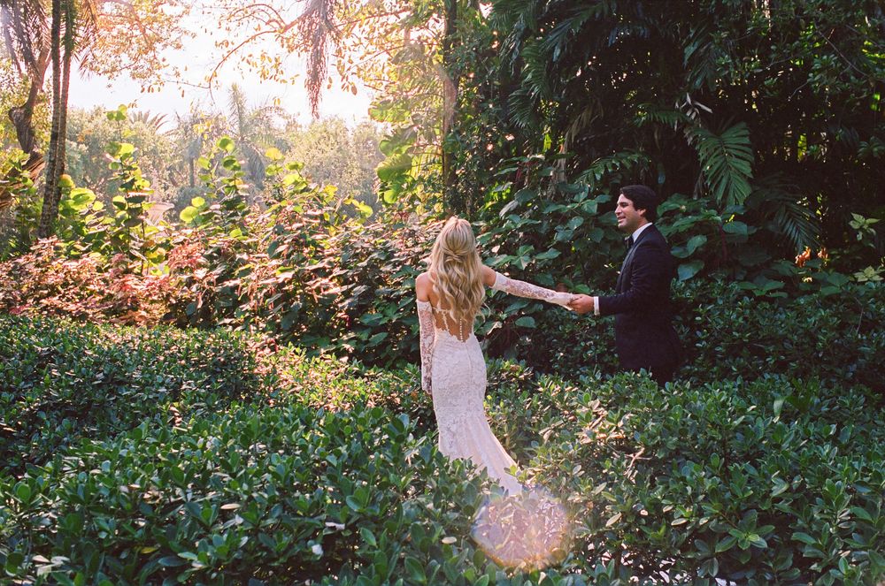 A couple dances together in a lush garden setting during golden hour.