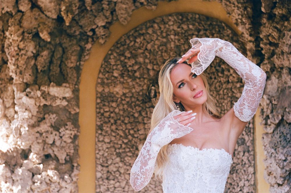 A romantic bridal photo collage showing four poses of a bride in a white lace gown against a stone wall background.