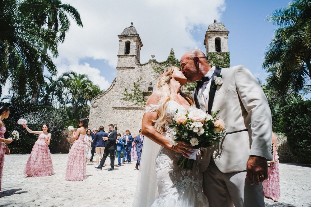 Tropical outdoor wedding celebration with palm trees and pink bridesmaid dresses creating a festive atmosphere.
