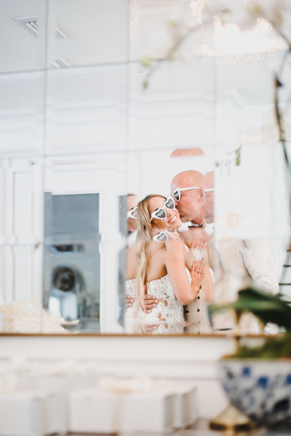 A couple shares an intimate moment while toasting with wine glasses in a bright white interior setting.