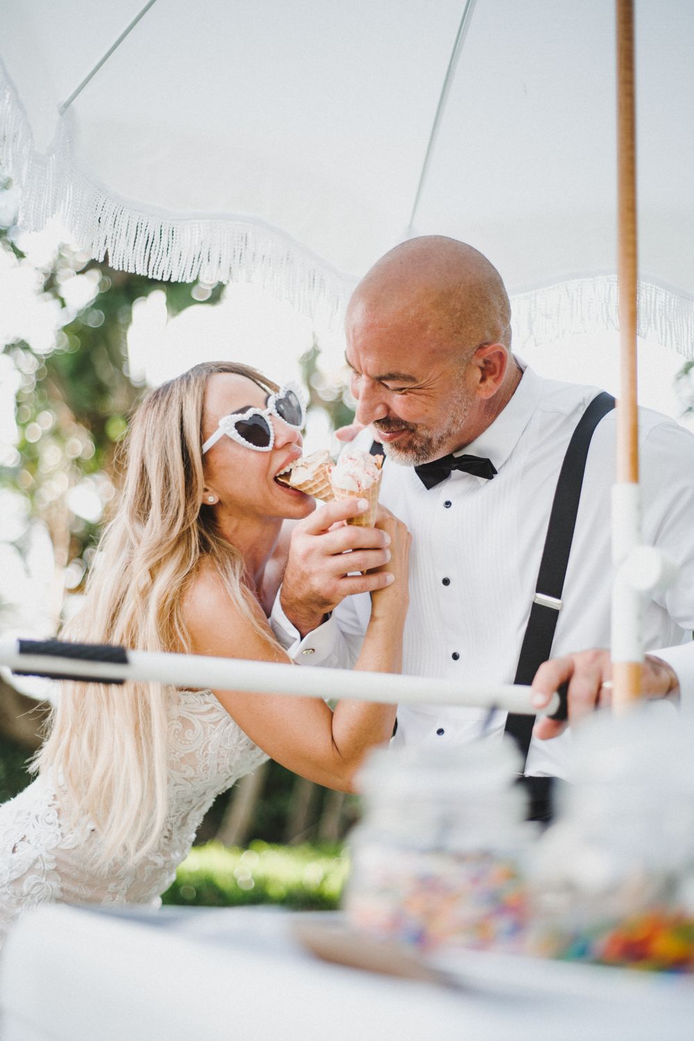 A couple shares intimate moments during their wedding reception under a white tent.