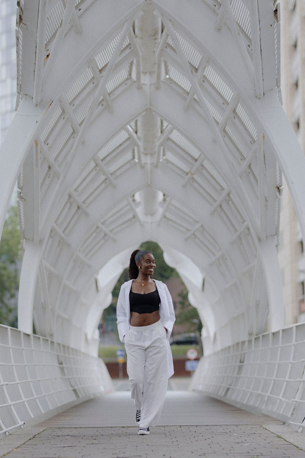 Person in white athletic wear performs dynamic movements in a modern white architectural tunnel or corridor.