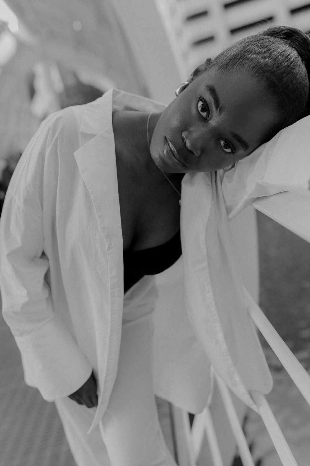 A black and white artistic portrait series showing graceful movement and flowing white fabric against a light background.