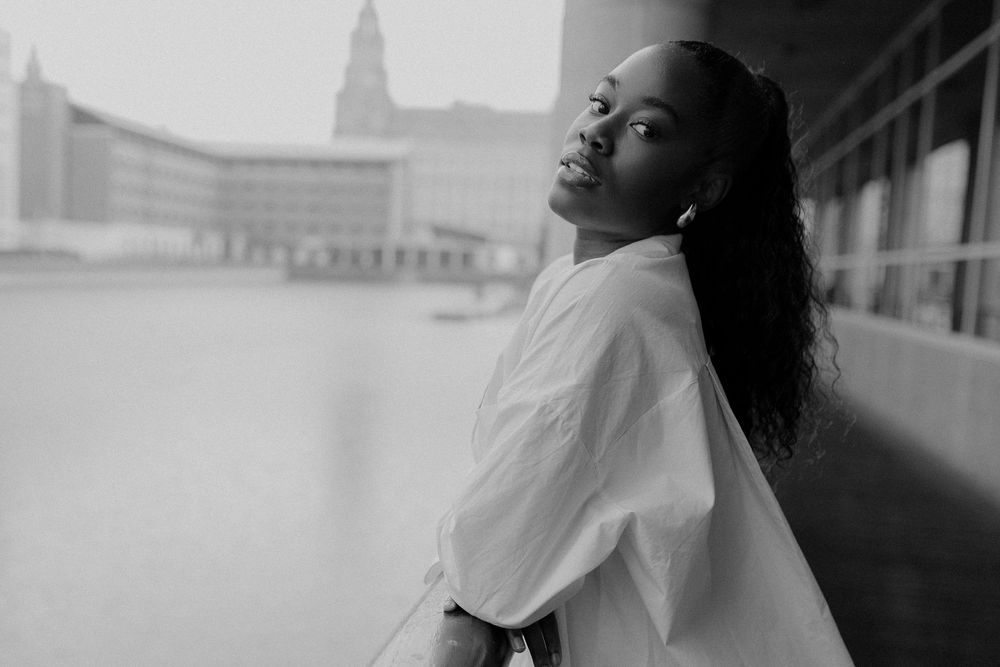A series of black and white photos showing a person in contemplative poses against urban backgrounds.