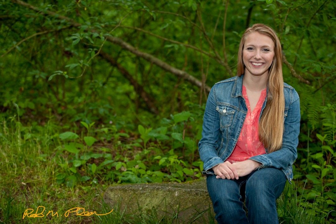 High school senior female at Nathan Chapman Memorial trail, Puyallup, sitting on rock.
